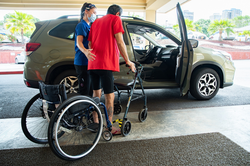 Rehab staff member assisting spinal cord injury patient Rehab staff member assisting patient