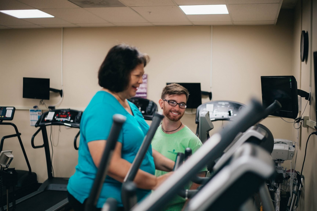 trainer helping woman on workout machine