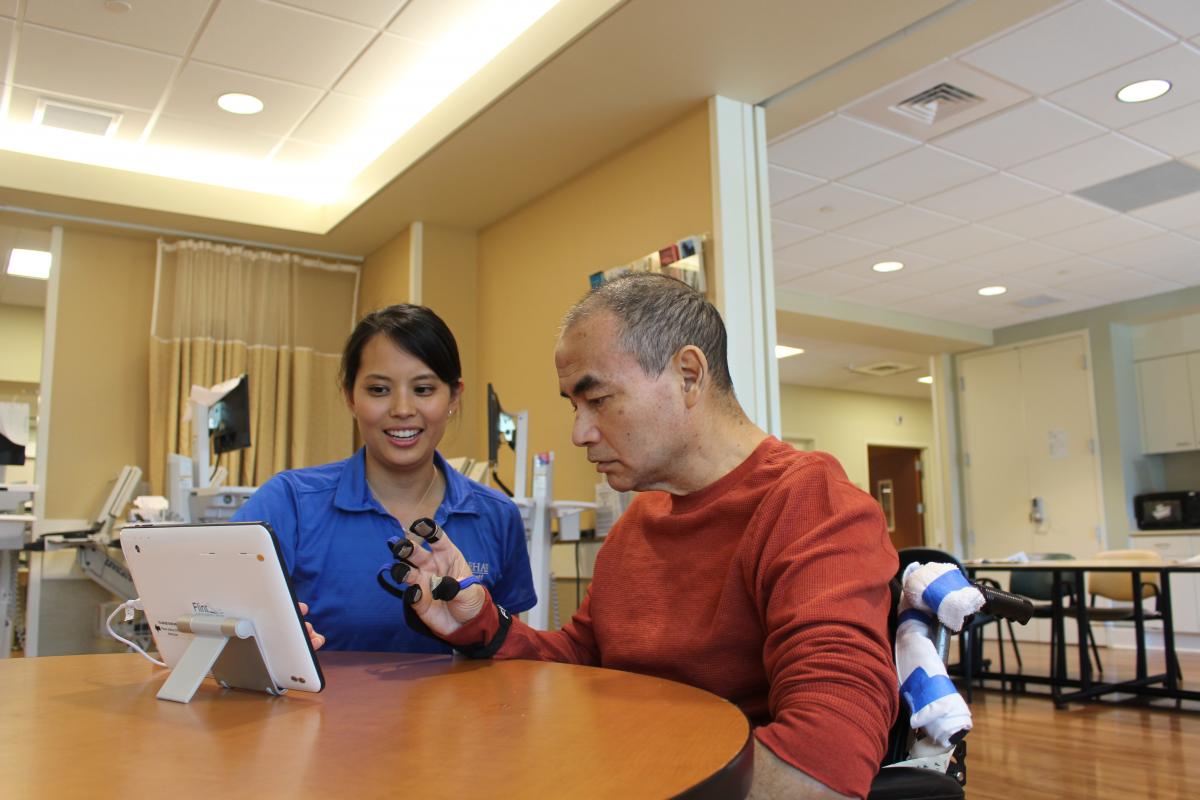 Staff member working with a patient using Music Glove technology