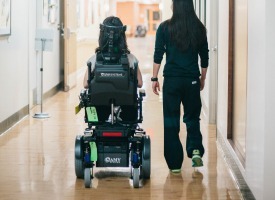 patient in wheelchair walking with staff