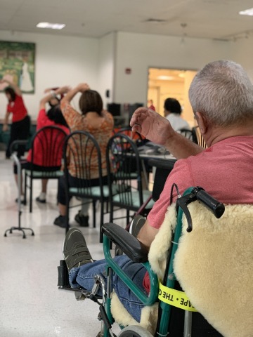 Elderly people sitting in chairs and stretching