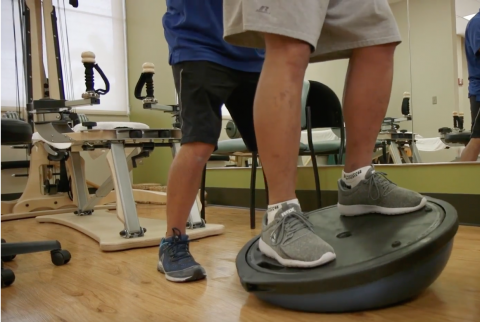 trainer helping patient on balance ball