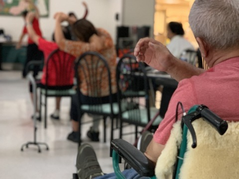 Elderly people sitting in chairs and stretching