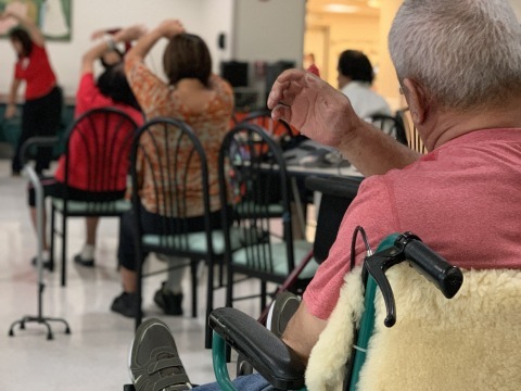 Elderly people sitting in chairs and stretching
