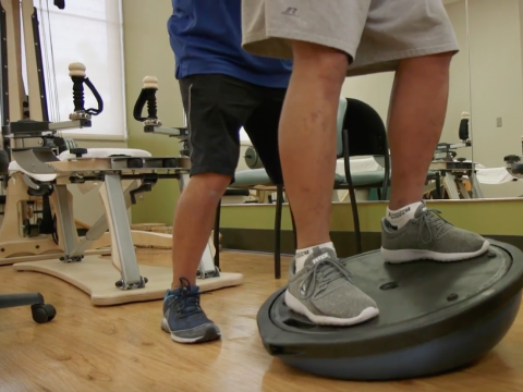 trainer helping patient on balance ball