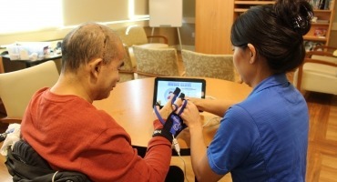 Rehab staff member helping traumatic brain injury patient using music glove technology